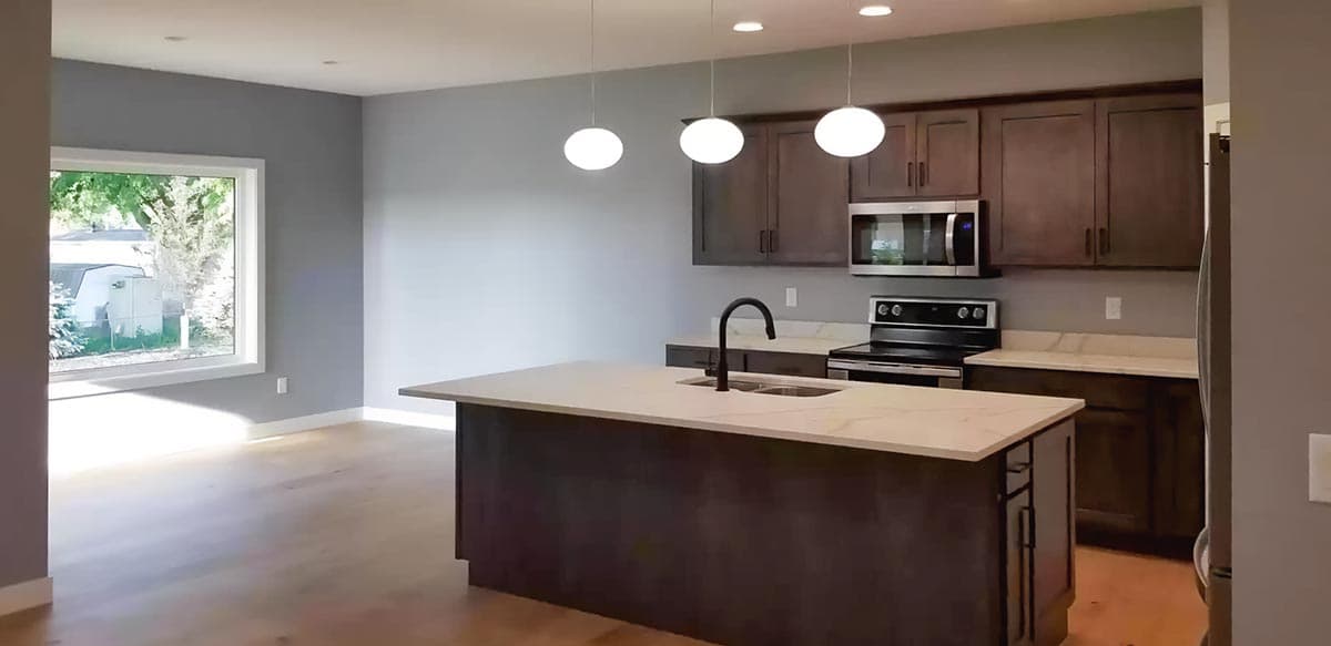 Open-concept kitchen with island, dark wood cabinets, white countertops, and stainless steel appliances.