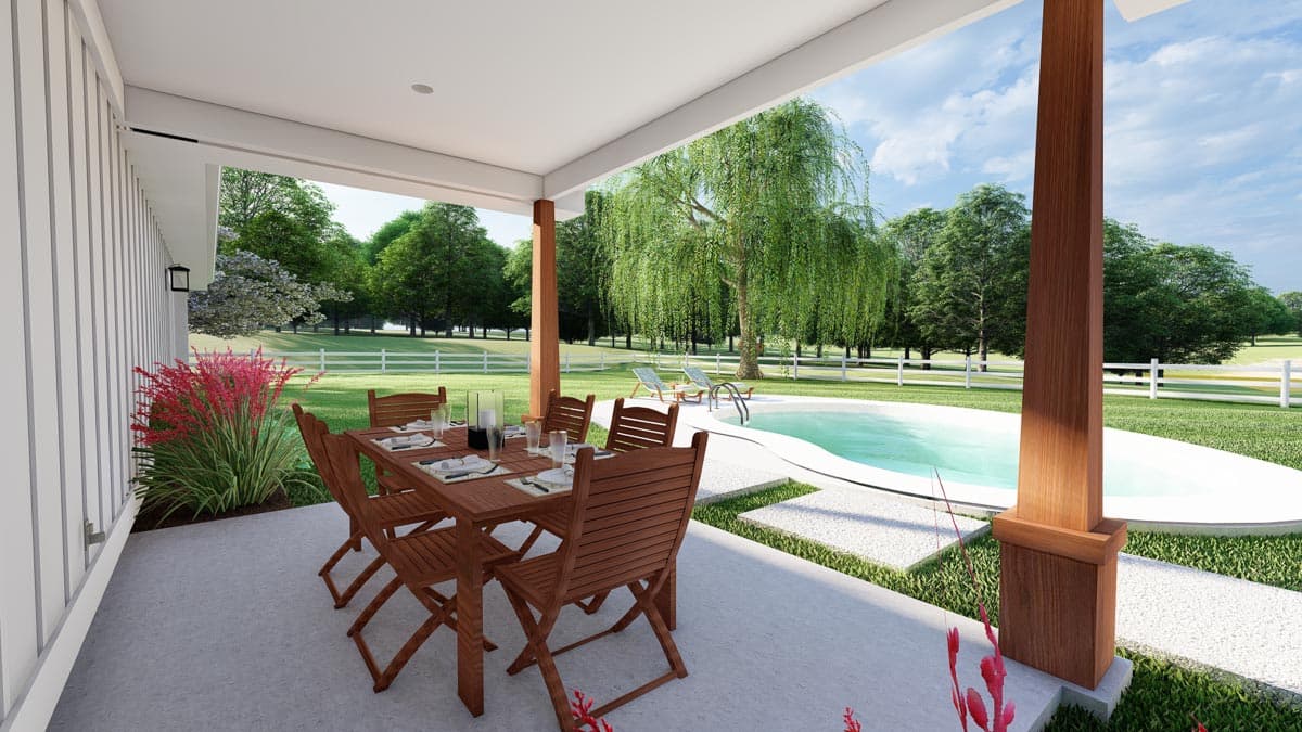 Covered patio with dining set overlooks pool and landscaped yard with white fence and trees.