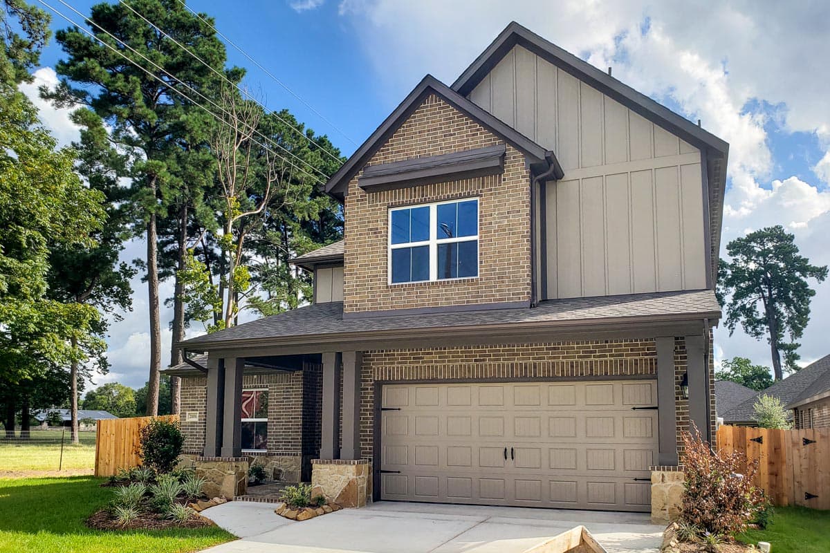 House plan exterior: Two-story, brick and vertical siding, covered front porch with stone accents, and attached garage.