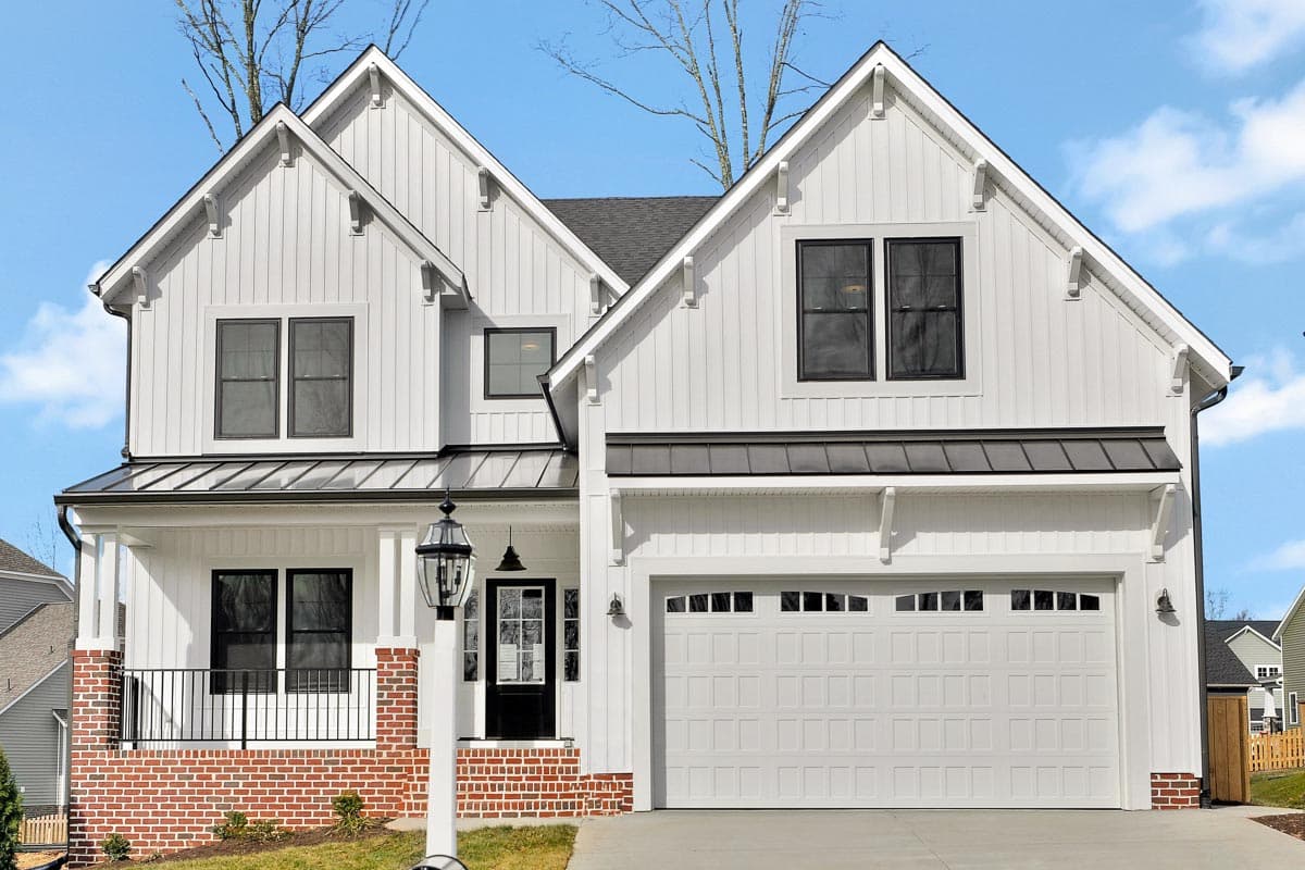 Modern Farmhouse house plan exterior with white vertical siding, gables, metal roof accents, covered porch, and attached garage.
