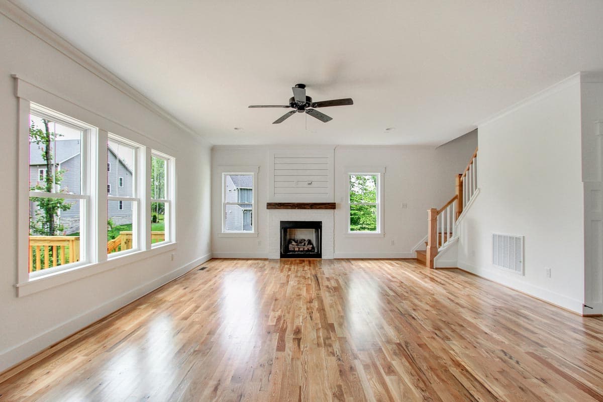 Interior view of a house plan showing a great room with fireplace, wood floors, and staircase.