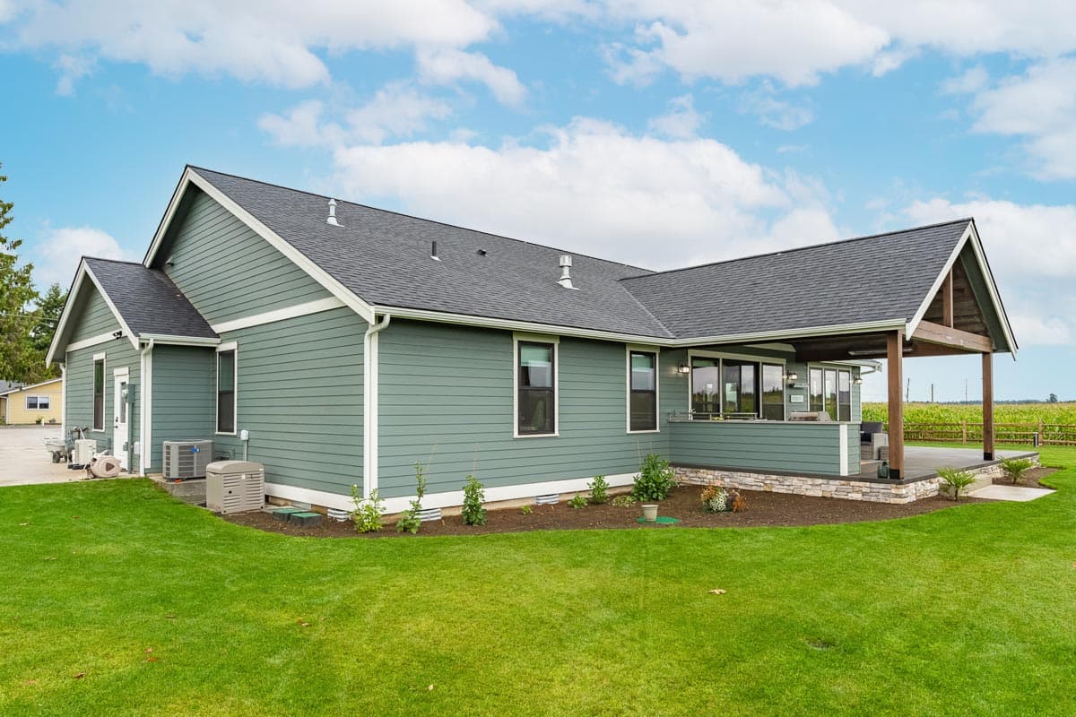 House plan exterior with horizontal siding, multiple gables, covered patio with exposed beams, and large windows.