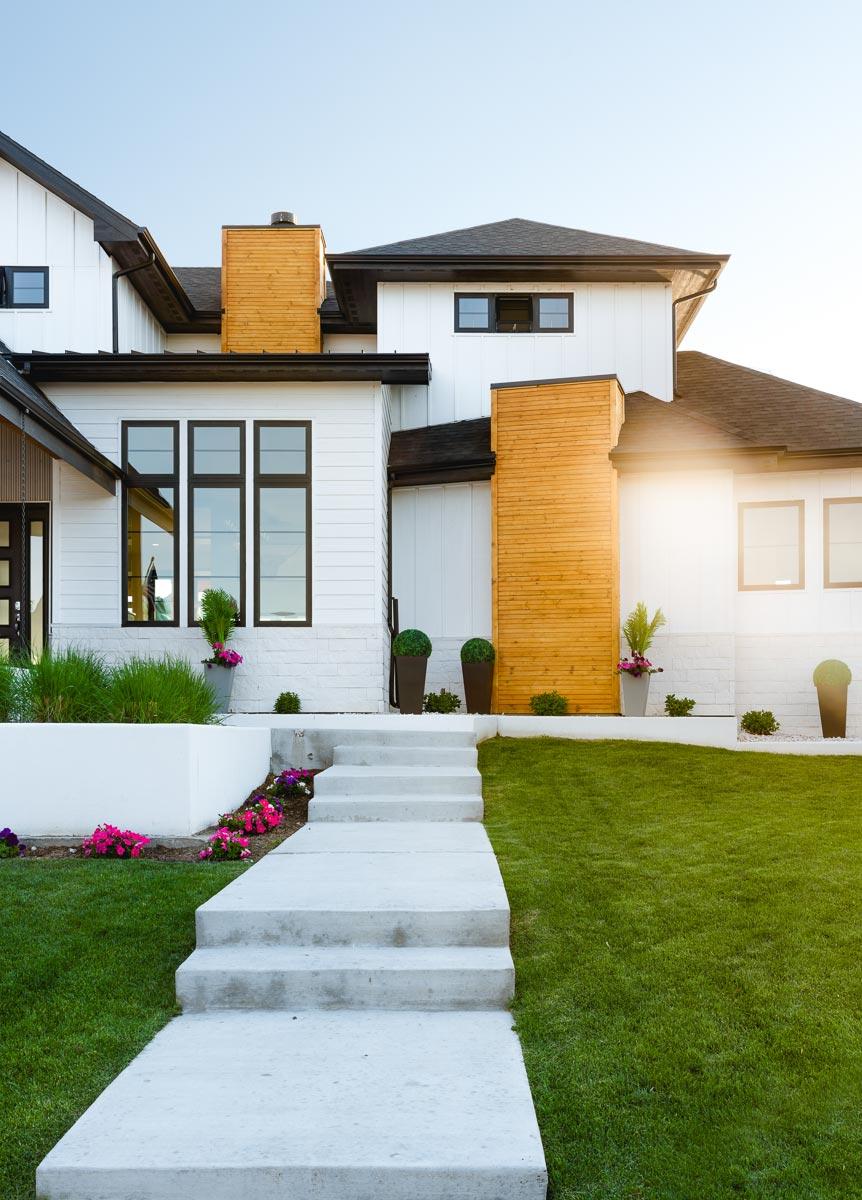 House plan exterior: Modern style with white siding, wood accents, dark framed windows, and multiple rooflines.