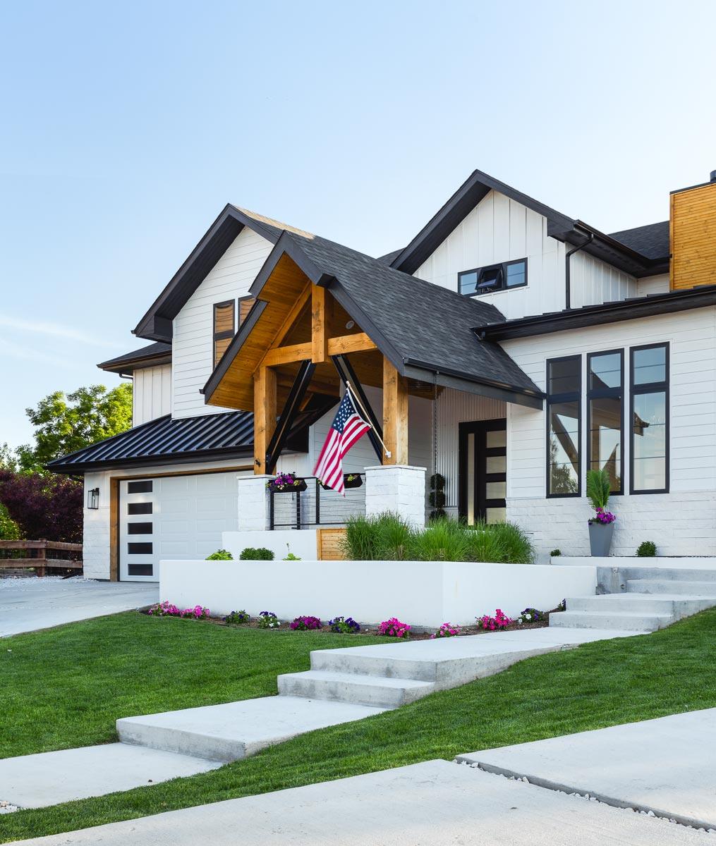 Modern Farmhouse house plan exterior with exposed wood beams, a white board and batten facade, black gables, and a multi-pane garage door.