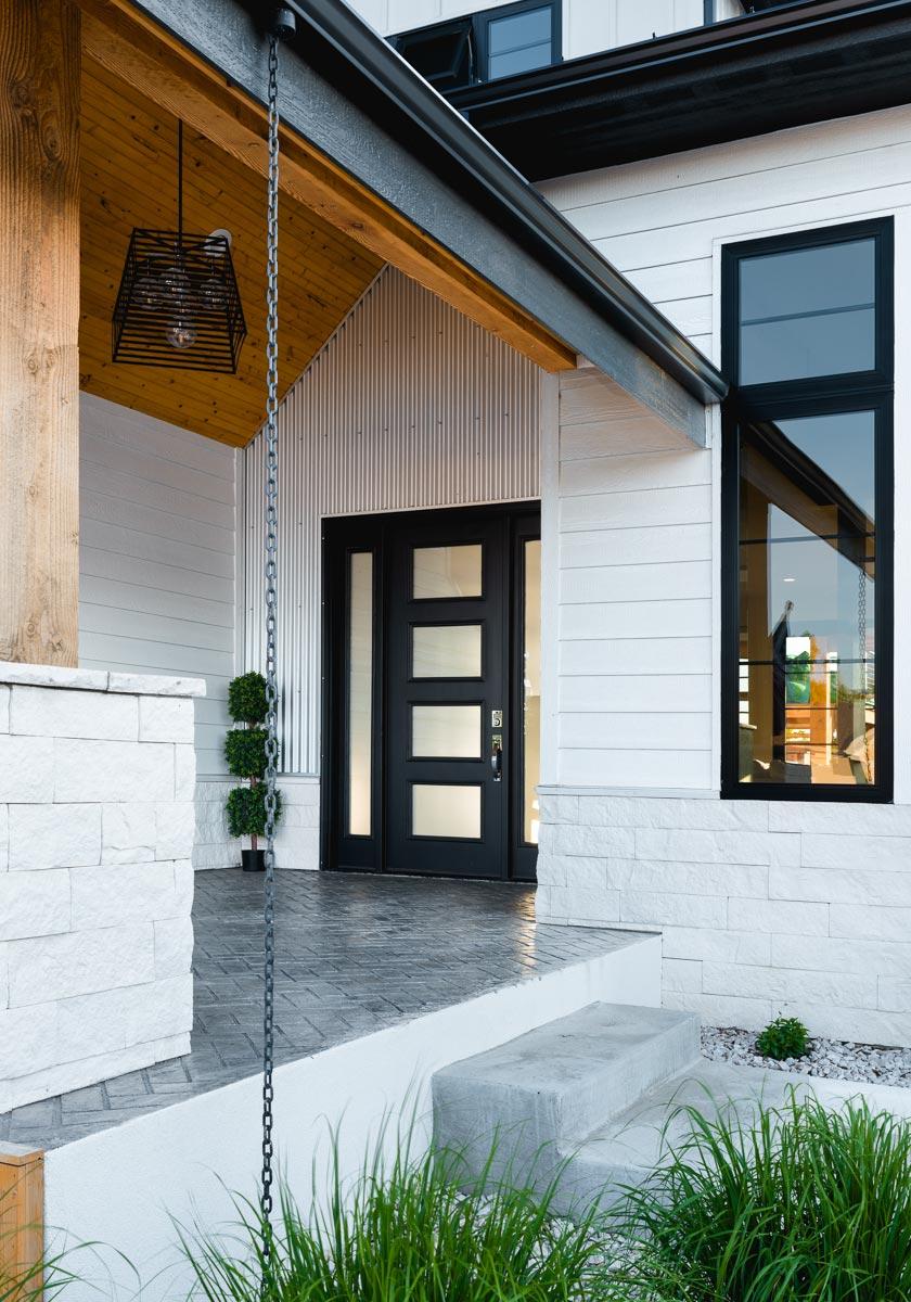 House plan exterior: Modern style with white siding, stone base, large black-framed windows, and a black modern door.