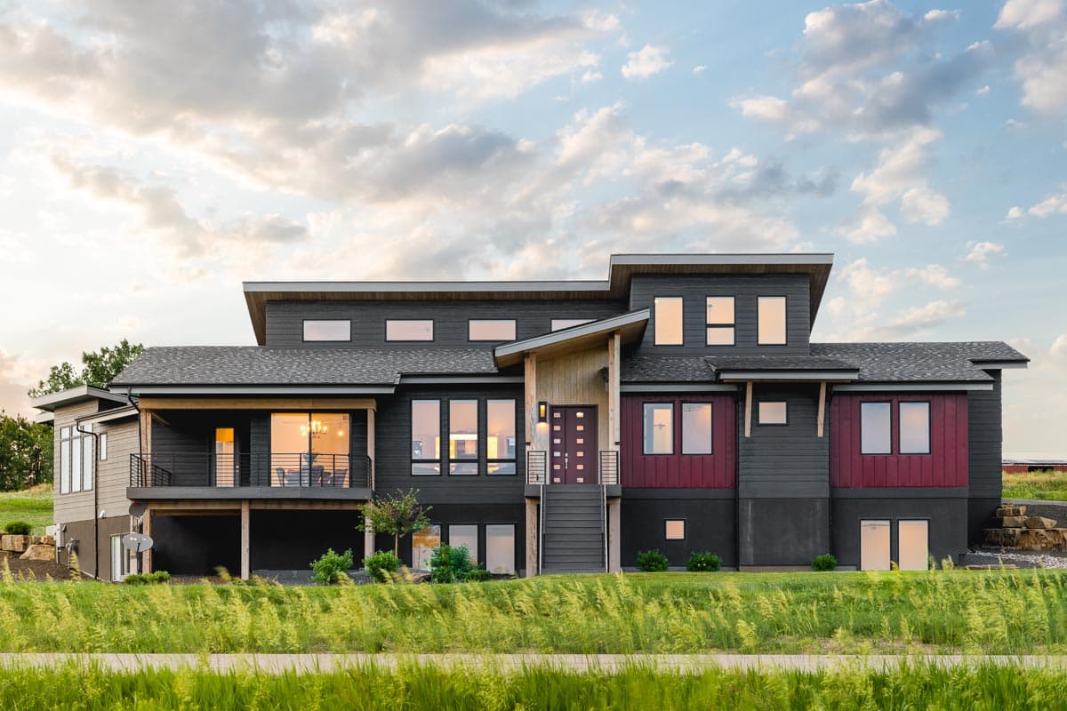 House plan exterior. Two-story Modern house with a flat roof, prominent dormers, and a covered porch. Features include board and batten siding.