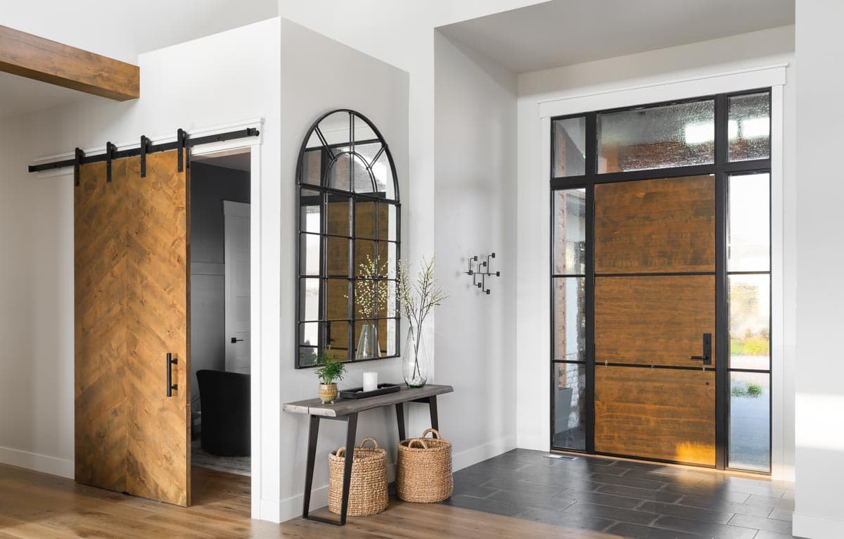 Interior entryway featuring a herringbone wood barn door, console table with arched mirror, and wood and glass entry door.