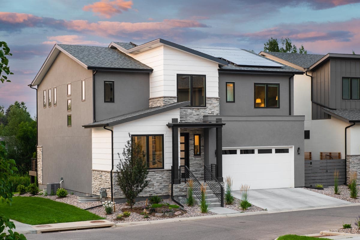 Modern house plan exterior with solar panels, stucco and stone accents, pitched rooflines, and a two-car garage.