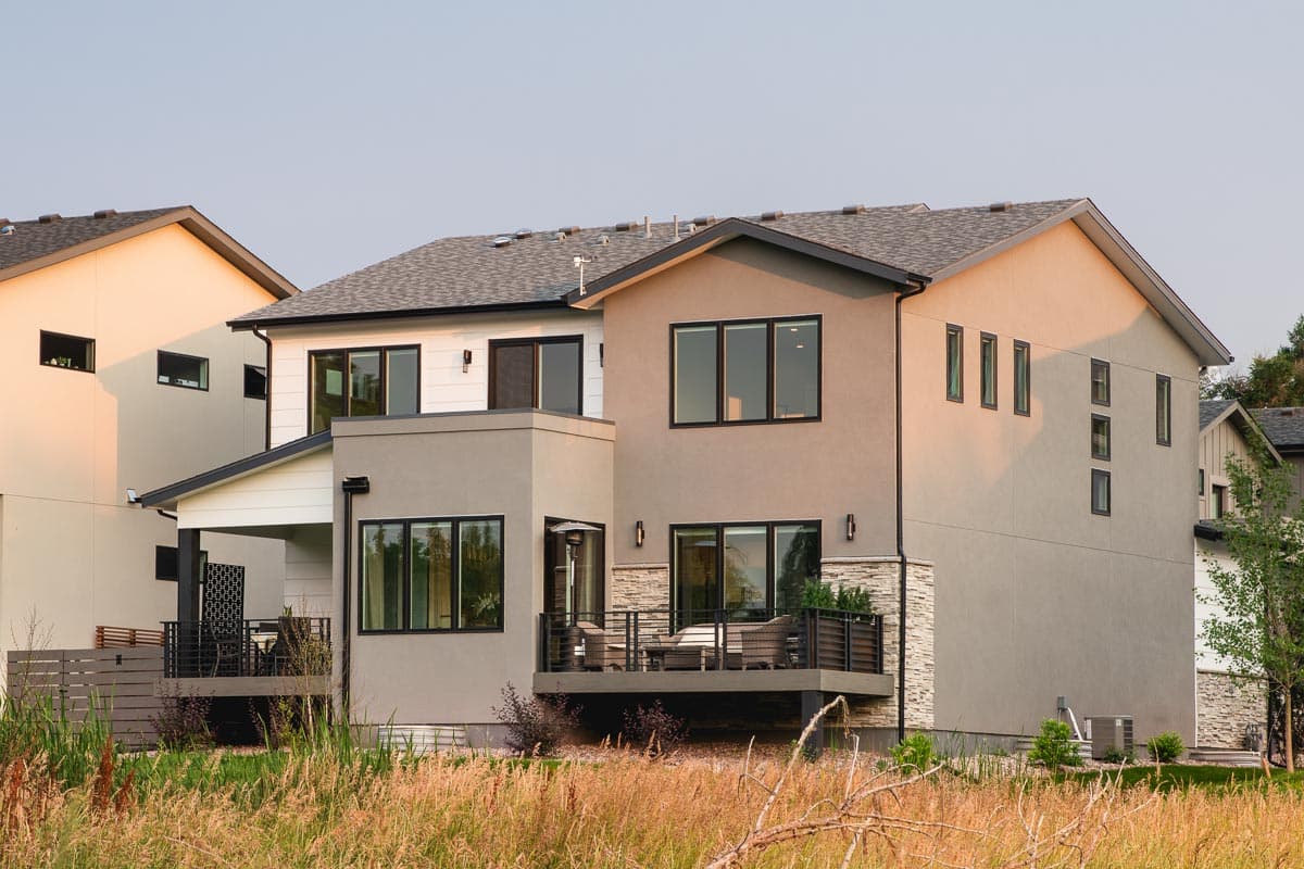 Modern two-story house plan exterior with stucco, stone accents, multiple gables, and a covered porch.