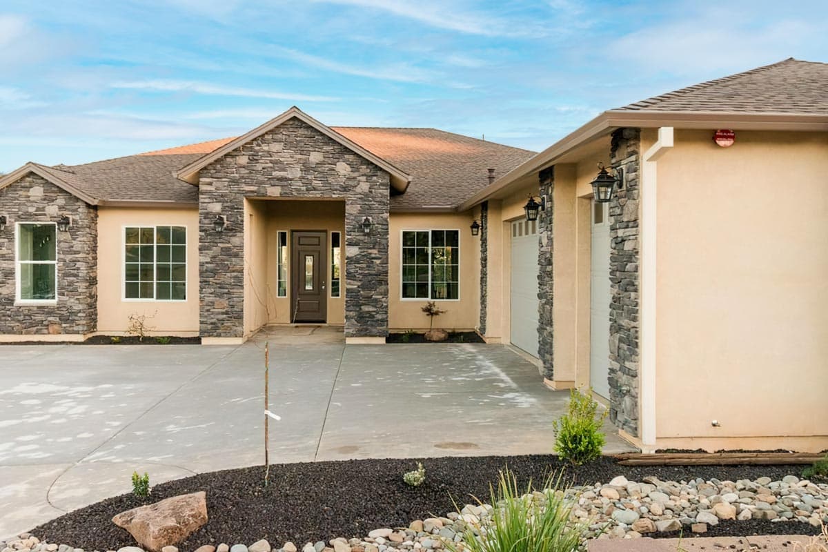 House plan exterior: Ranch style with stone accents, covered entry, and attached three-car garage.