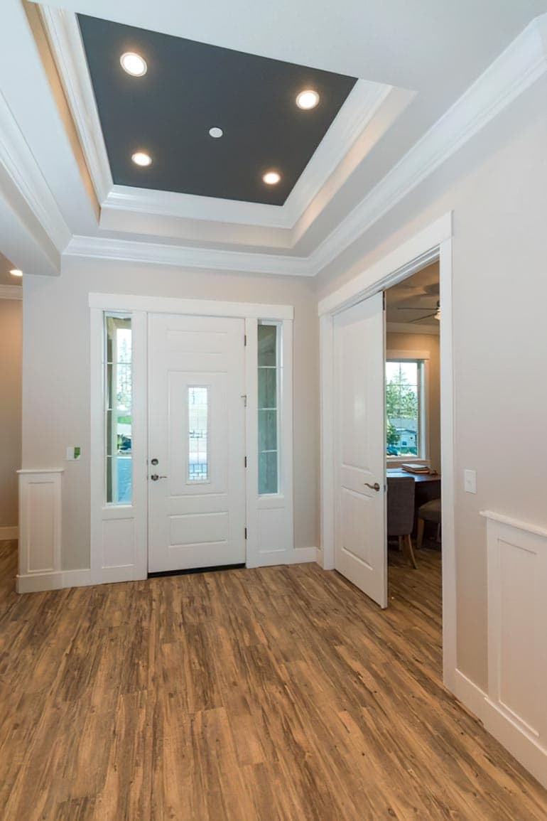 Foyer interior view with double doors, sidelights, recessed lighting, and a dark-paneled tray ceiling.