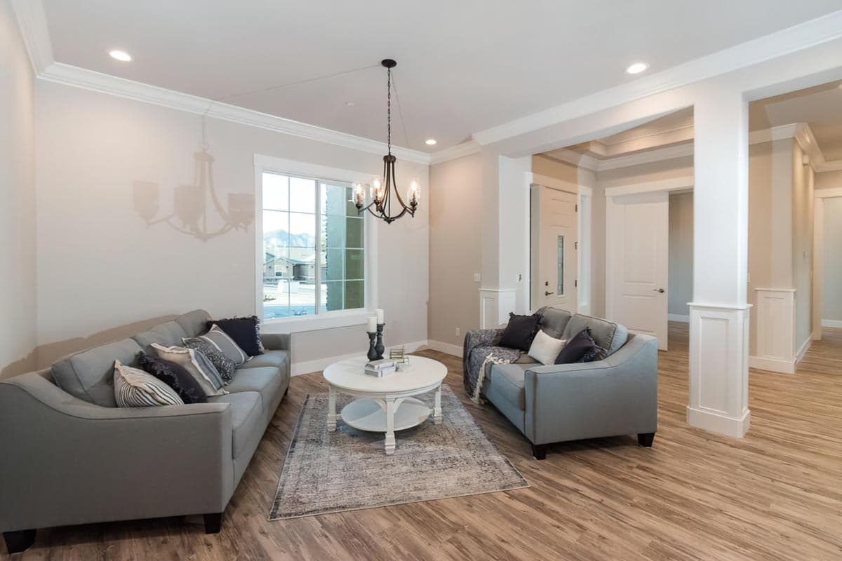 Interior view: Living room with two gray sofas, white round coffee table, area rug, and coffered ceiling.
