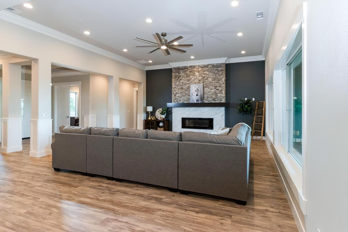 Great room with stone fireplace, large sectional sofa, and wide plank flooring.