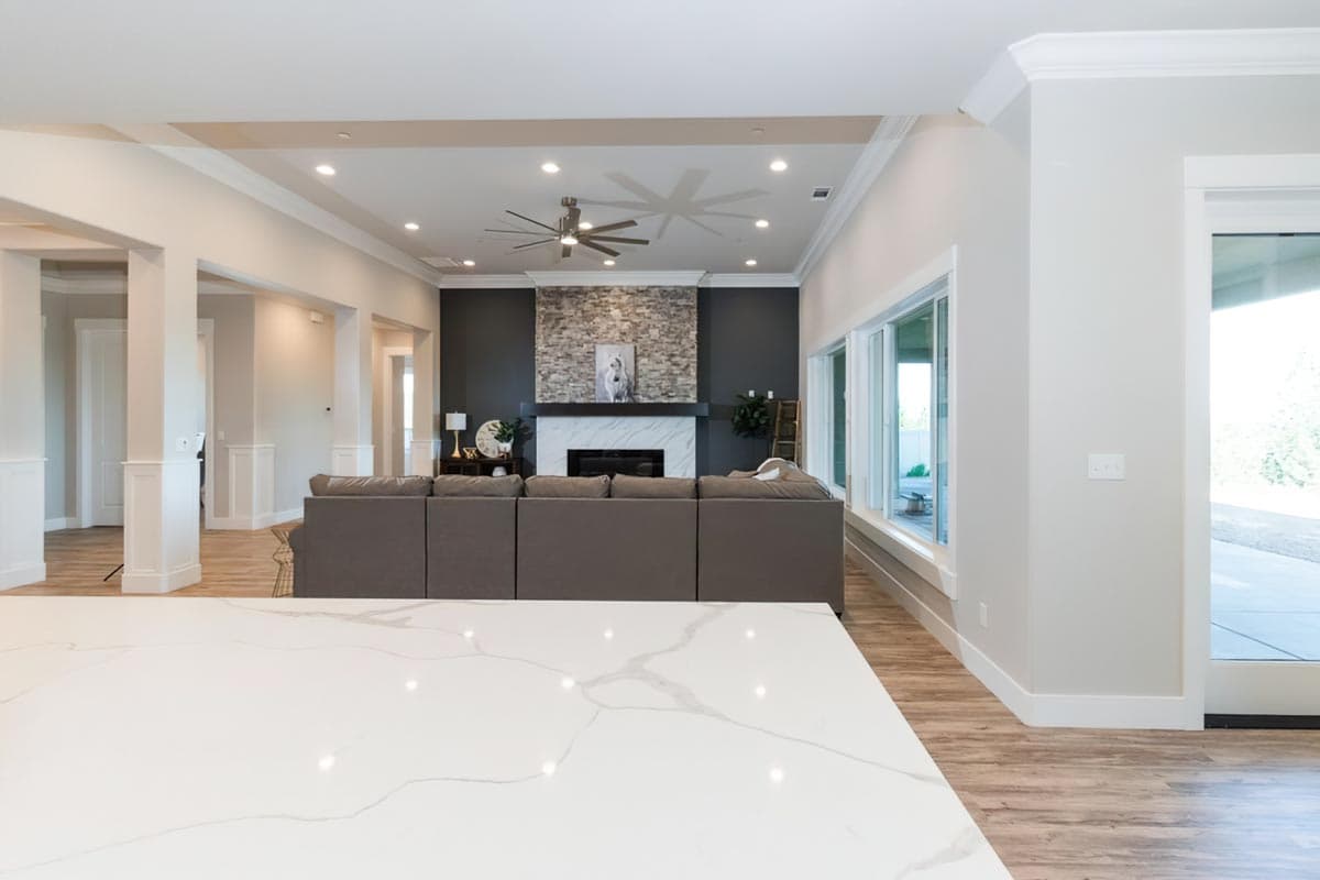 Open concept living area with stone fireplace, large windows, and sectional sofa.