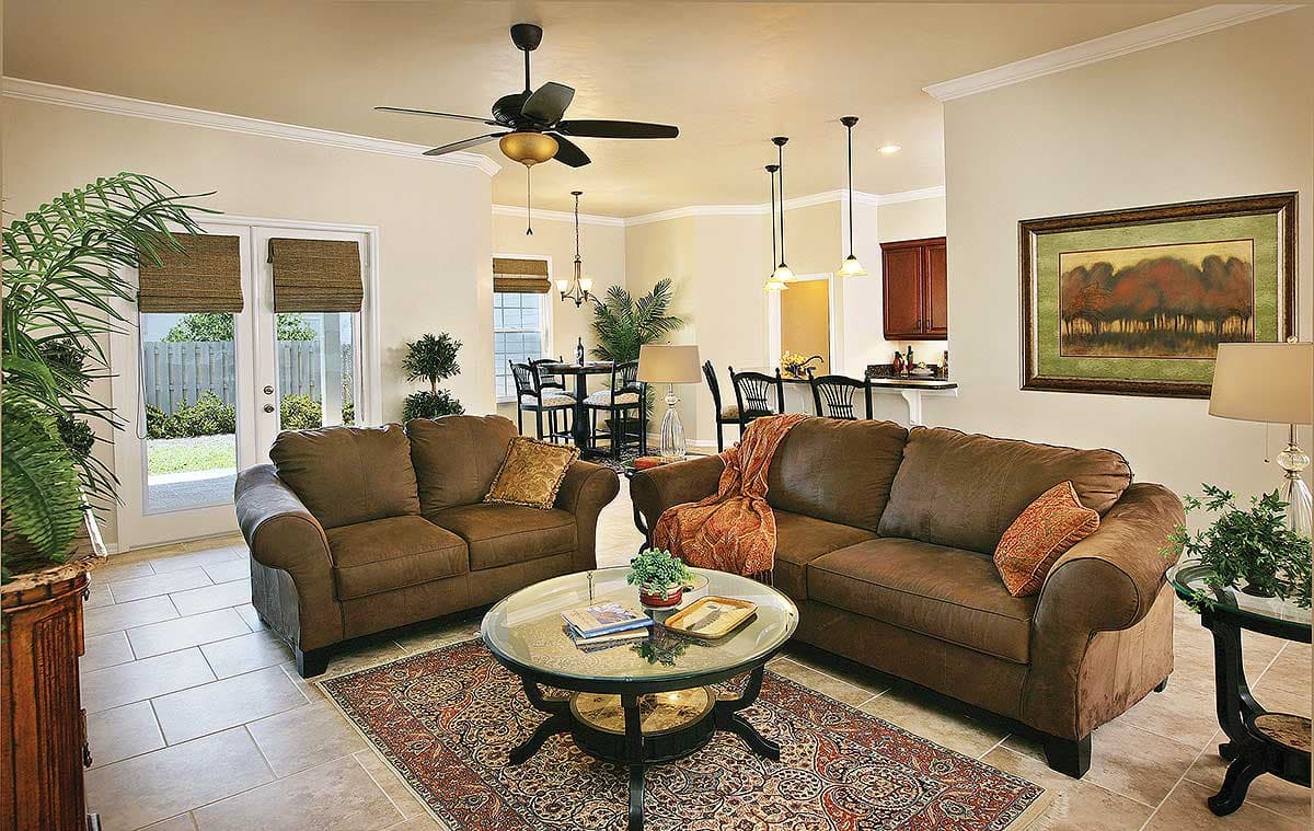 Open-concept living area with two sofas, coffee table, ceiling fan, and view into kitchen and dining areas.
