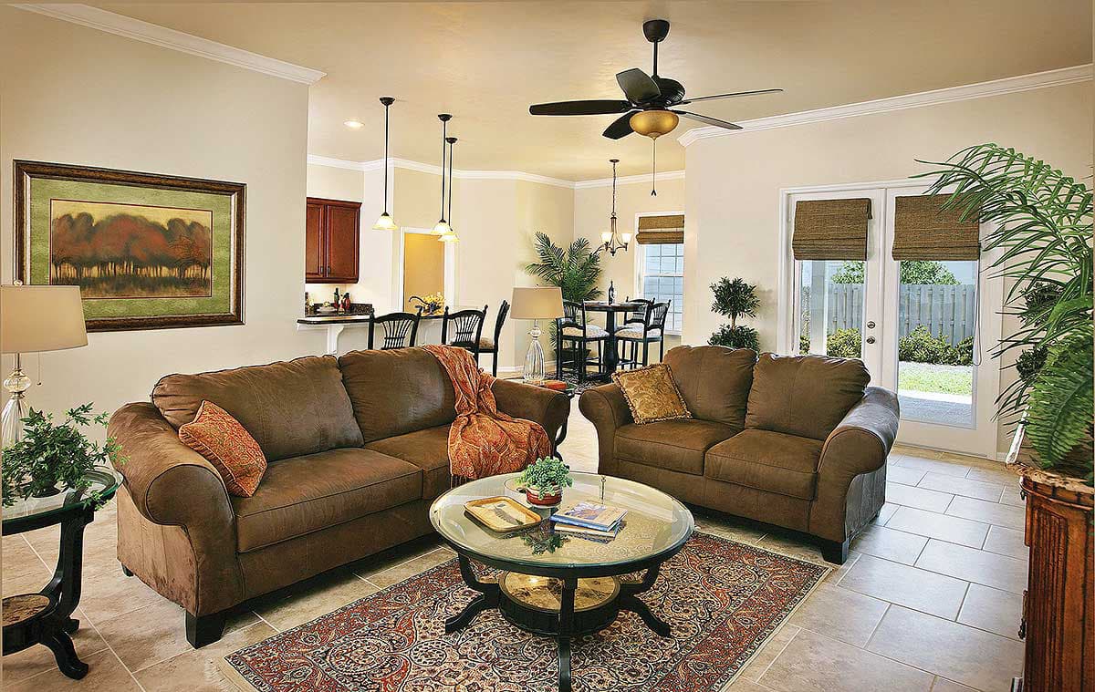 Open concept living area with sofa, coffee table, dining area, and kitchen island, with access to a patio.