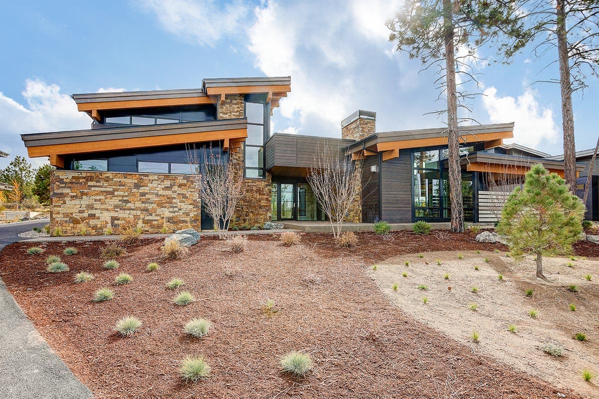 Modern house plan exterior with stacked stone, wood siding, and dramatic cantilevered rooflines.