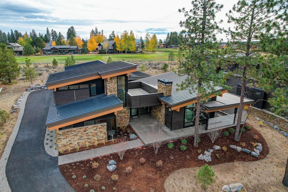 Modern house plan exterior with stone and wood siding, multiple gables, metal roof, and covered porch.