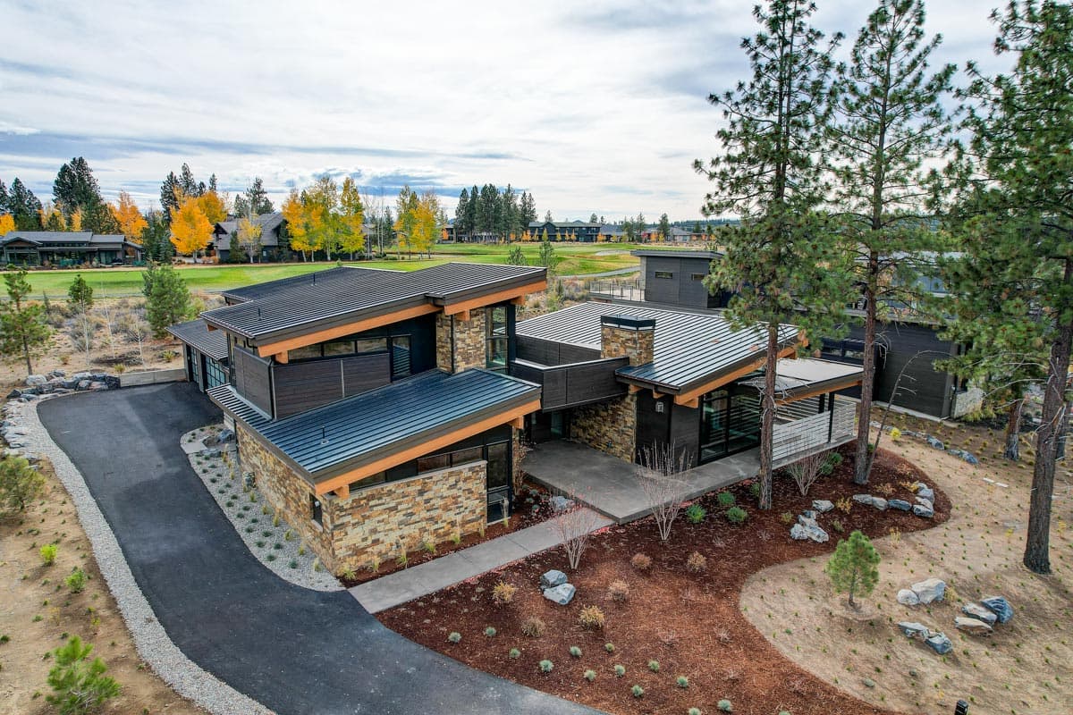 Modern house plan exterior with stone and wood siding, metal roof, multi-level rooflines, and attached garage.