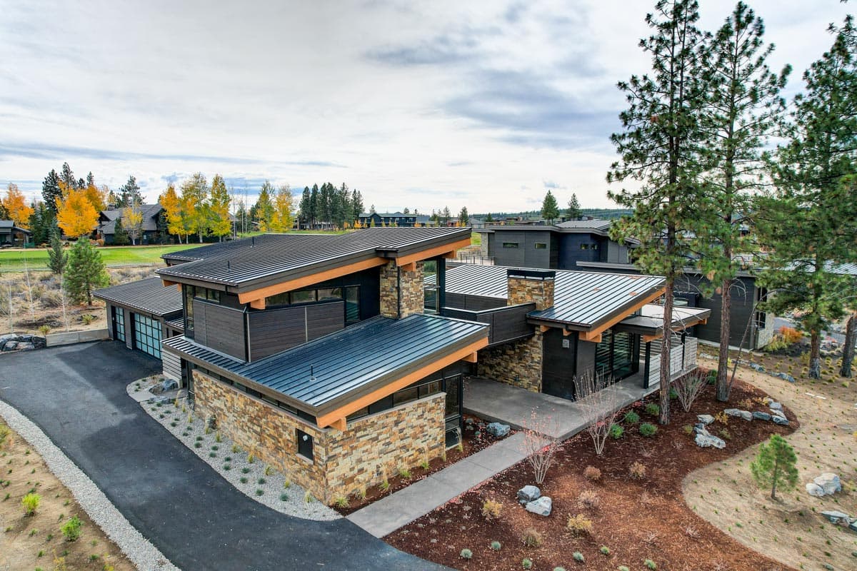 Modern house plan exterior with stone and wood facade, multiple gables, and metal rooflines.