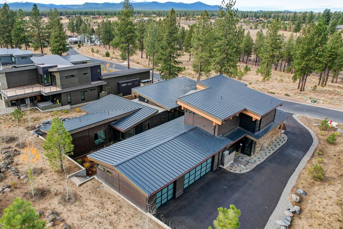 Modern multi-story house plan exterior with dark siding, metal roof, multiple gables, and attached garage.