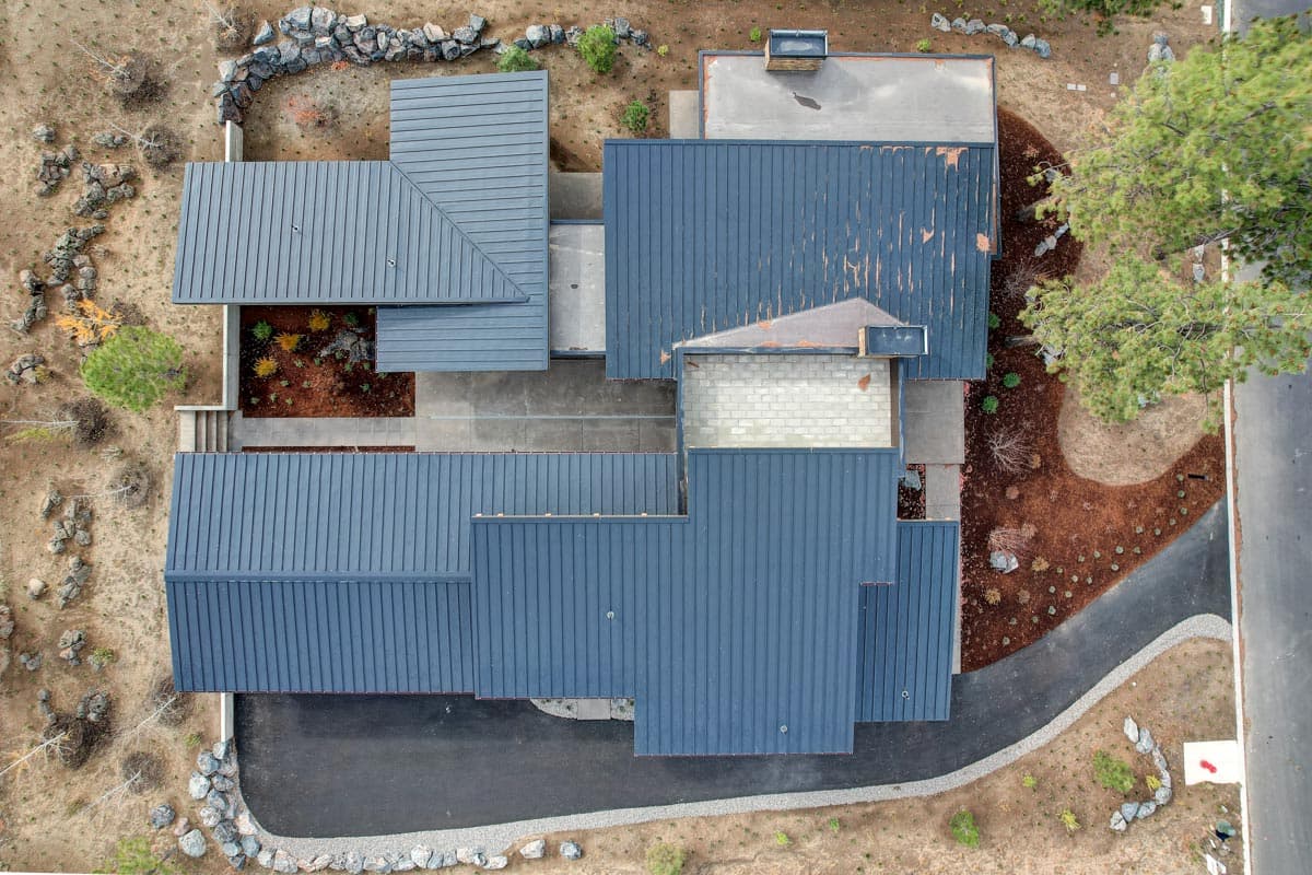House plan exterior showing a multi-gabled roofline with standing seam metal roofing and a visible chimney.