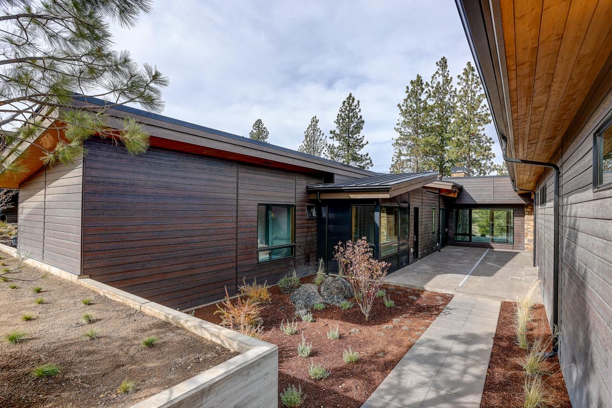 Modern house plan exterior with wood siding, large windows, and intersecting rooflines.