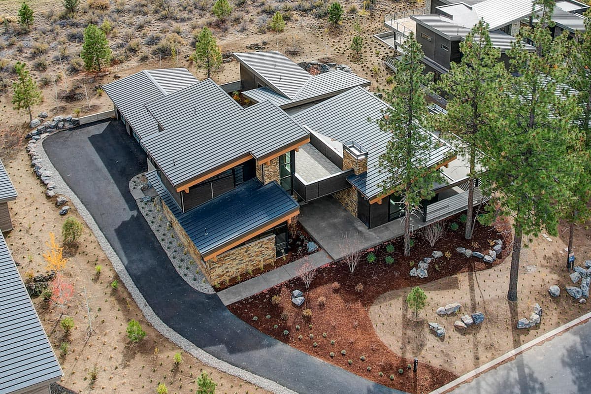 Modern house plan exterior with metal roof, stone and wood accents, multiple gables, and a three-car garage.
