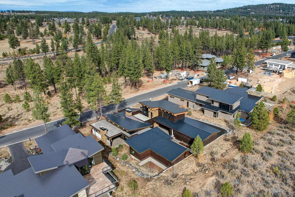 Modern house plan exterior with low-pitched roofs, multiple gables, stone accents, and a flat-roofed section.