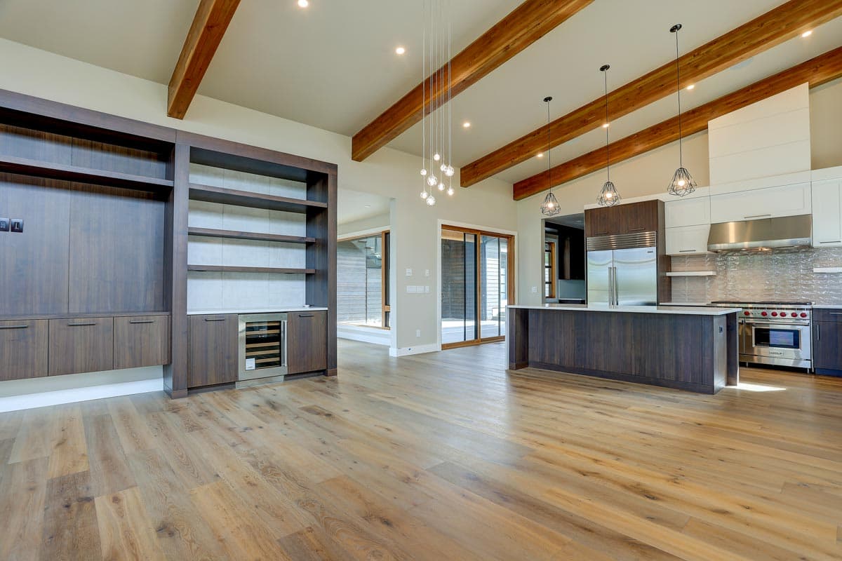 Open concept living area with beamed ceiling, built-in shelving, and modern kitchen with island and stainless steel appliances.