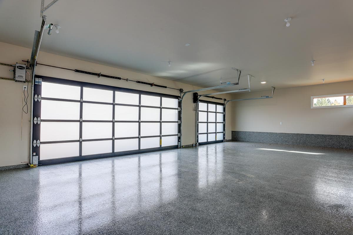 Garage interior with two frosted glass paneled garage doors, epoxy speckled flooring, and a narrow horizontal window.