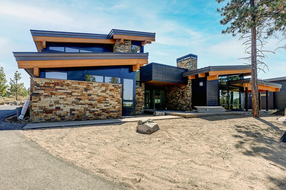 Modern house plan exterior featuring stacked stone, wood accents, flat rooflines, and large windows.