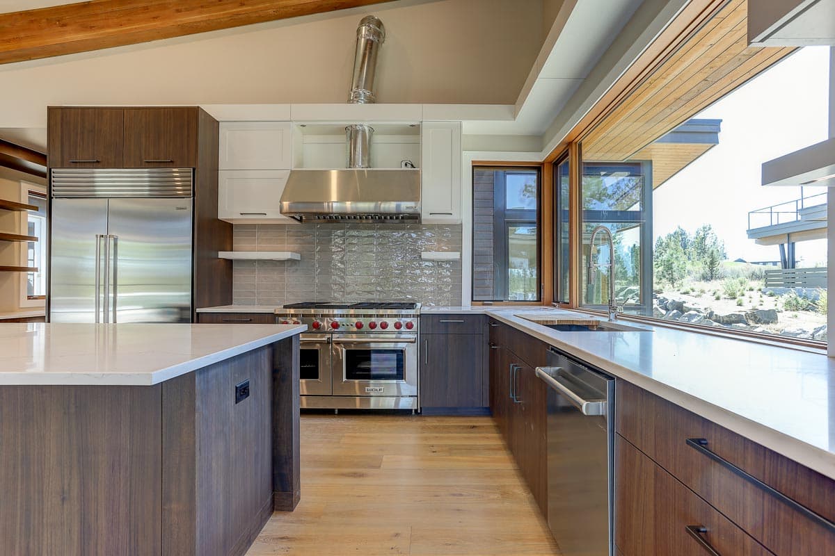 Modern kitchen with large island, stainless steel appliances, tiled backsplash, and expansive window views.