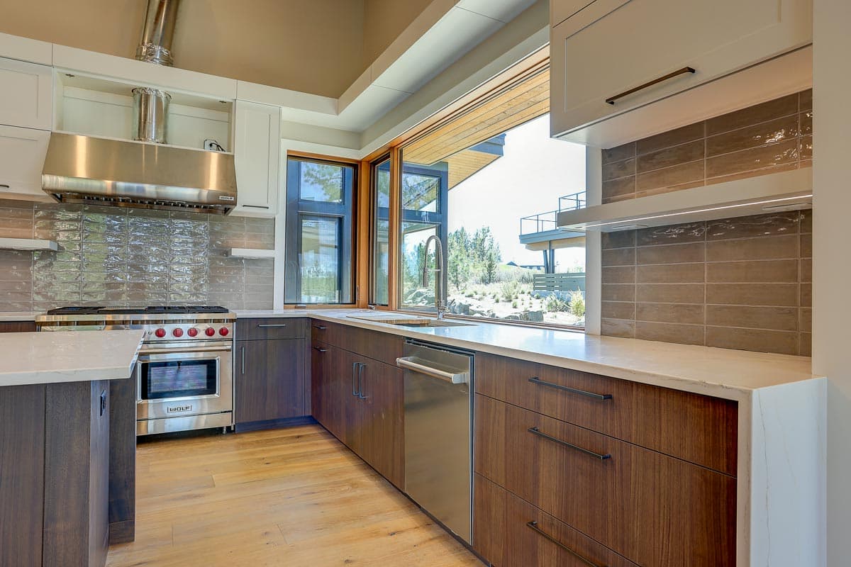Modern kitchen with dark wood cabinetry, stainless steel range and hood, and large folding window.