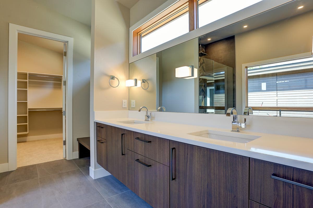 Modern bathroom with double floating vanity, large mirror, and doorway to walk-in closet.