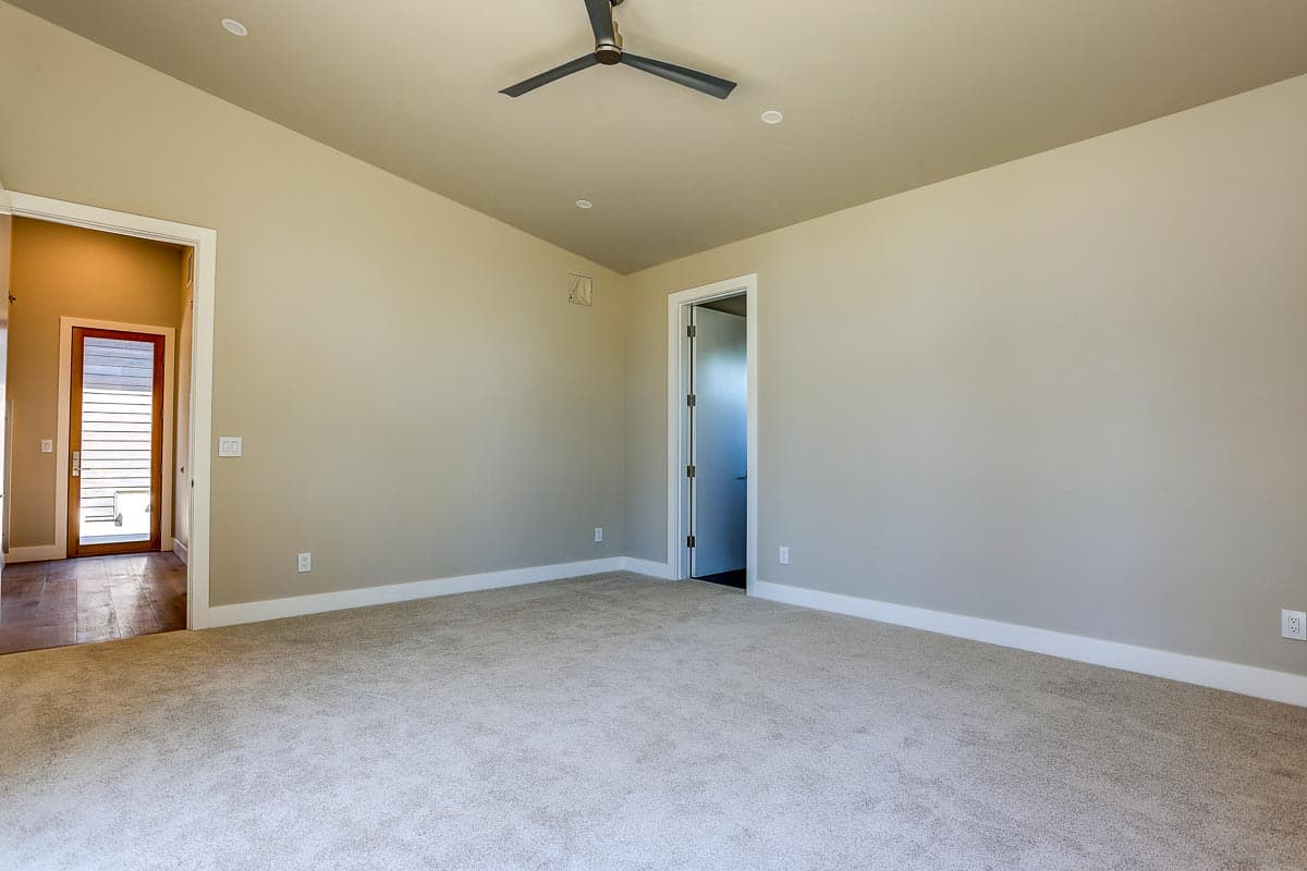 Interior view of a room with a ceiling fan and doors leading to another room and hallway.