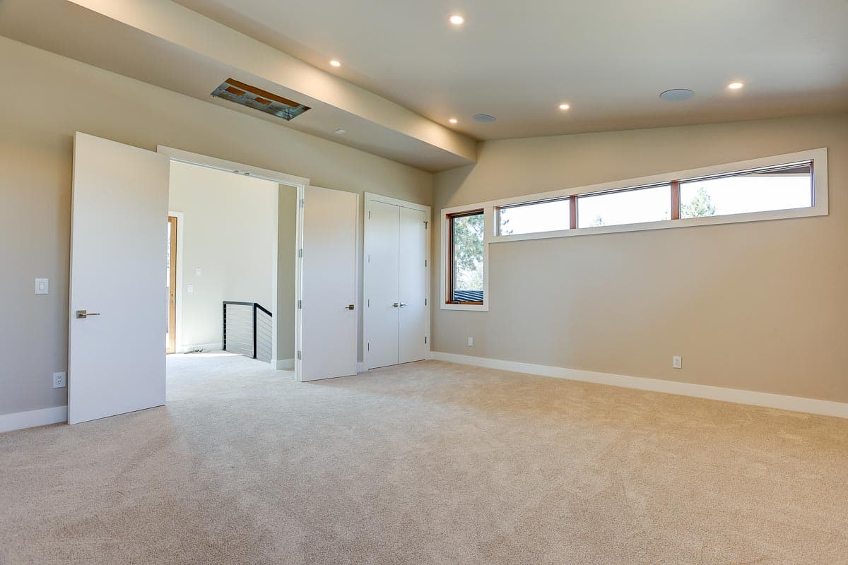 Interior view of a room with double doors, a long horizontal window, and recessed lighting.