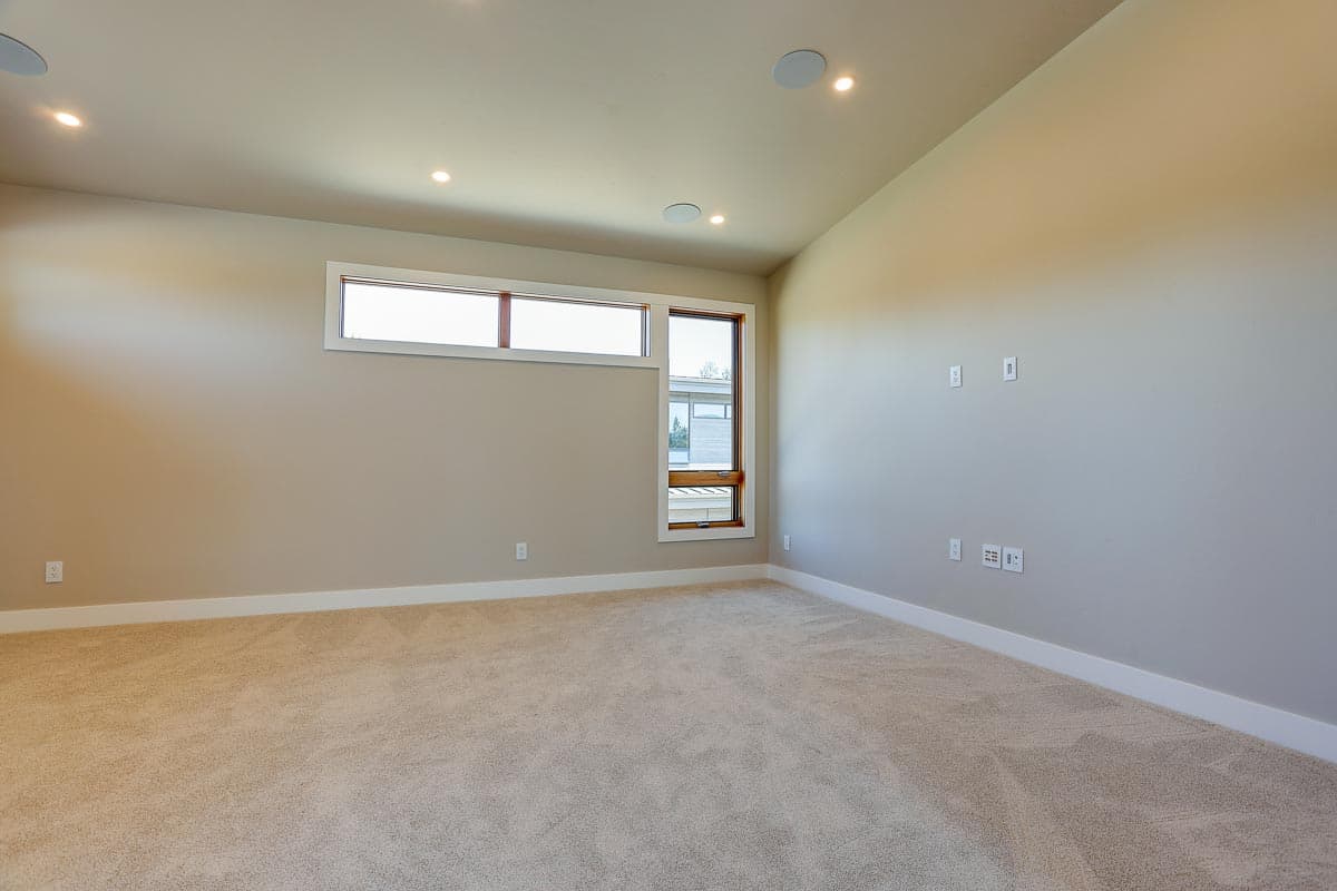 Interior view of carpeted room with beige walls, recessed lighting, and a horizontal band of windows.