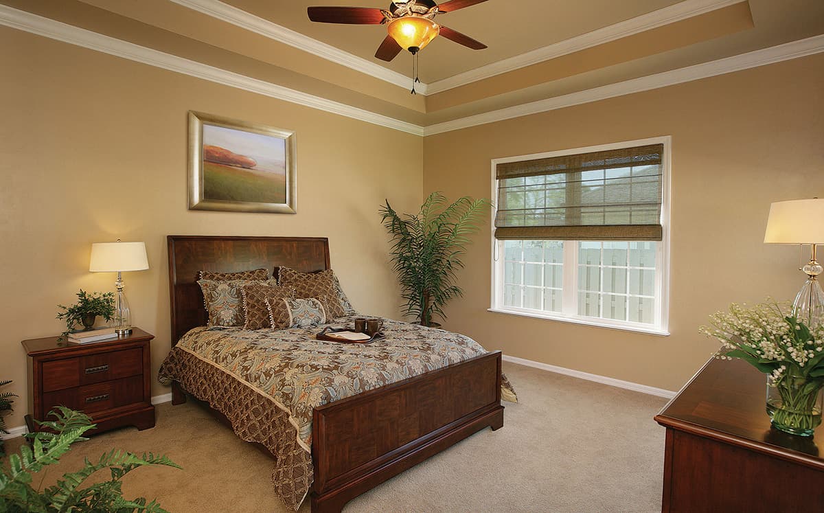 Bedroom with a coffered ceiling, large window with grid panes, and wood furniture.
