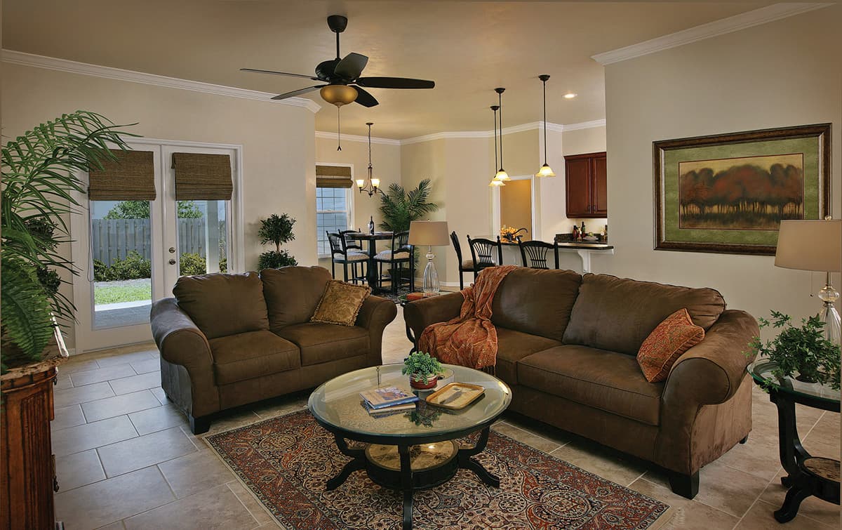 Living room with dual sofas, glass coffee table, pendant lights, ceiling fan, and French doors leading outdoors.