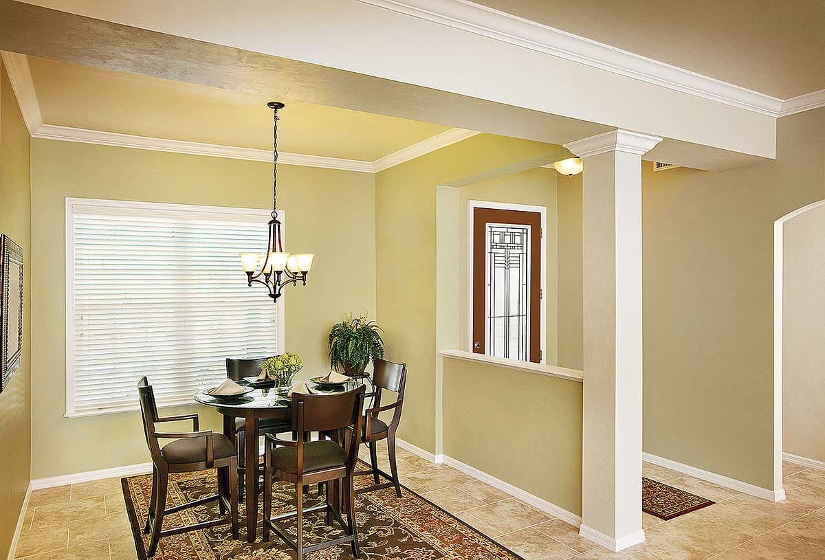 Dining area with a round table, four chairs, chandelier, and view of a glass-paneled door.