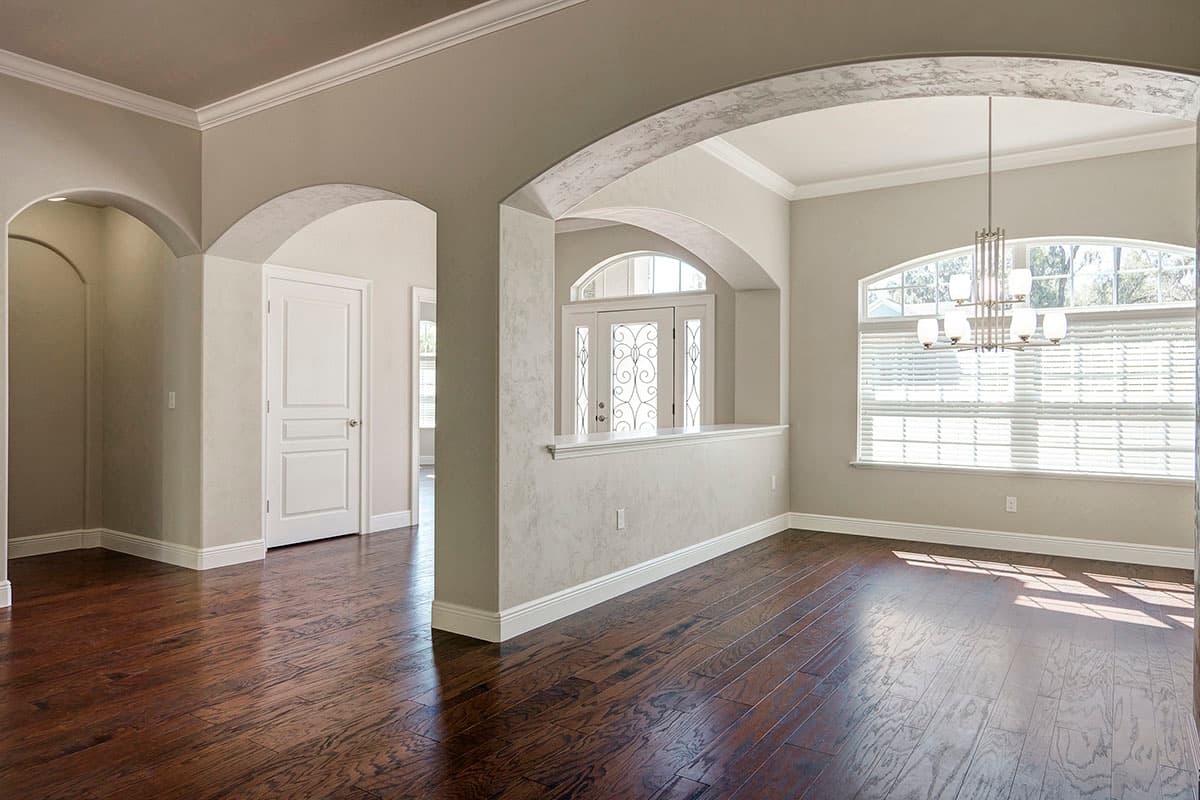 Interior rendering showing arched doorways, a decorative glass front door, and a large window with blinds in a dining area.