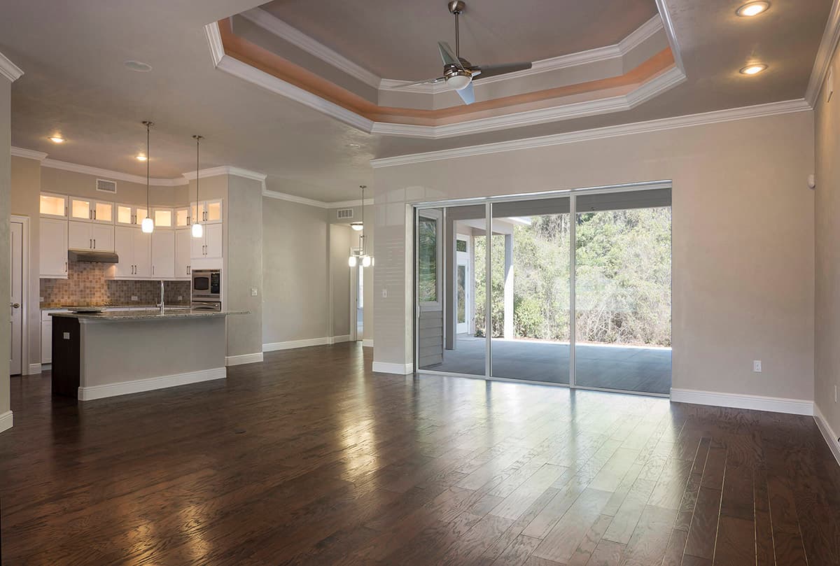 Interior view: kitchen with island, living area with tray ceiling and fan, and sliding glass doors to patio.