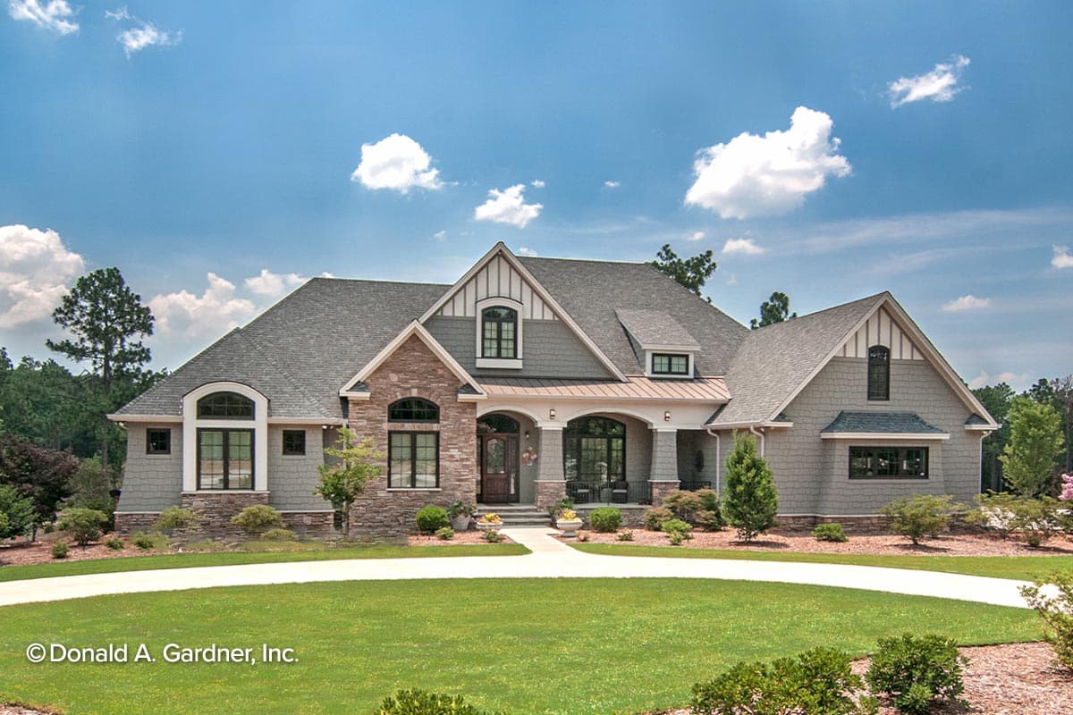 House plan exterior: Two-story home with arched windows, stone accents, gabled dormers, and covered front porch with decorative columns.