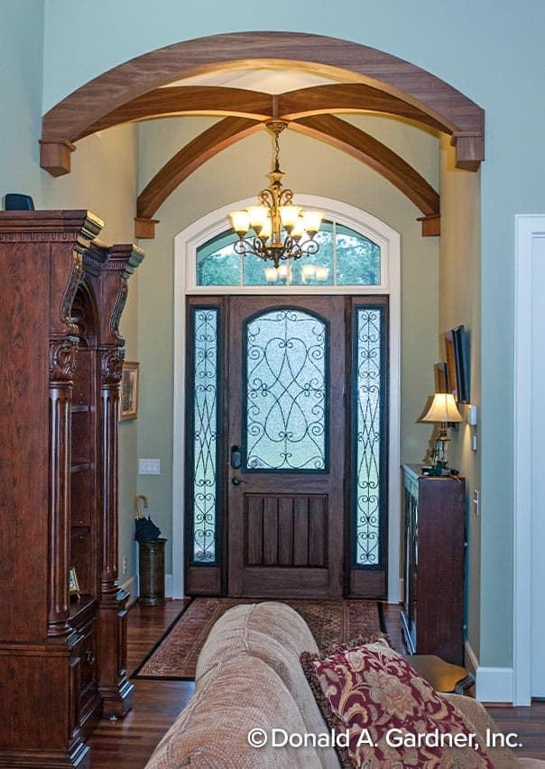 Interior view of a home entryway featuring a wooden arched ceiling, decorative glass sidelights, and a dark wood front door.