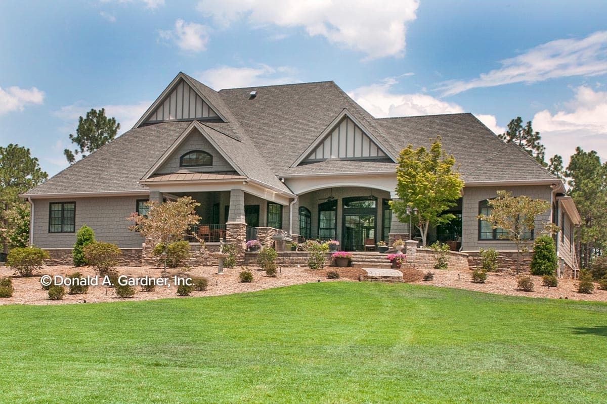 House plan exterior with gables, covered porch, stone accents, and multiple rooflines.