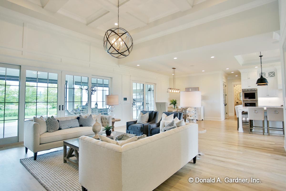 Interior view of living room and kitchen with coffered ceiling, large windows, and island.