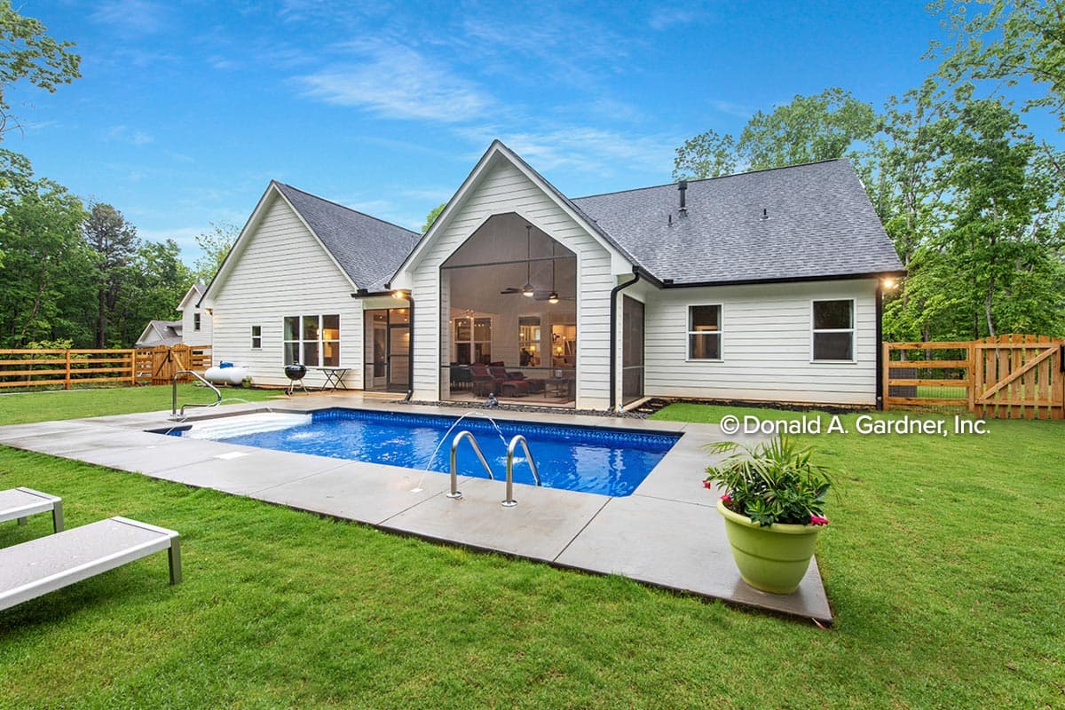 Modern Farmhouse house plan exterior with gabled roof, white siding, pool, and screened porch.
