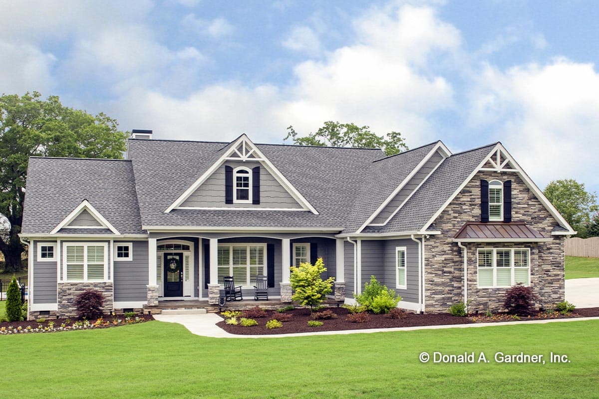 House plan exterior. Craftsman style, one story. Features include a covered porch, multiple gables with decorative trim, and stone accents.