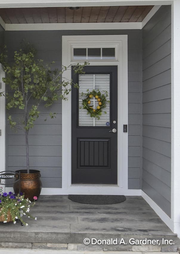 House plan exterior: Covered porch with gray siding, white trim, and a black paneled door with a transom window.
